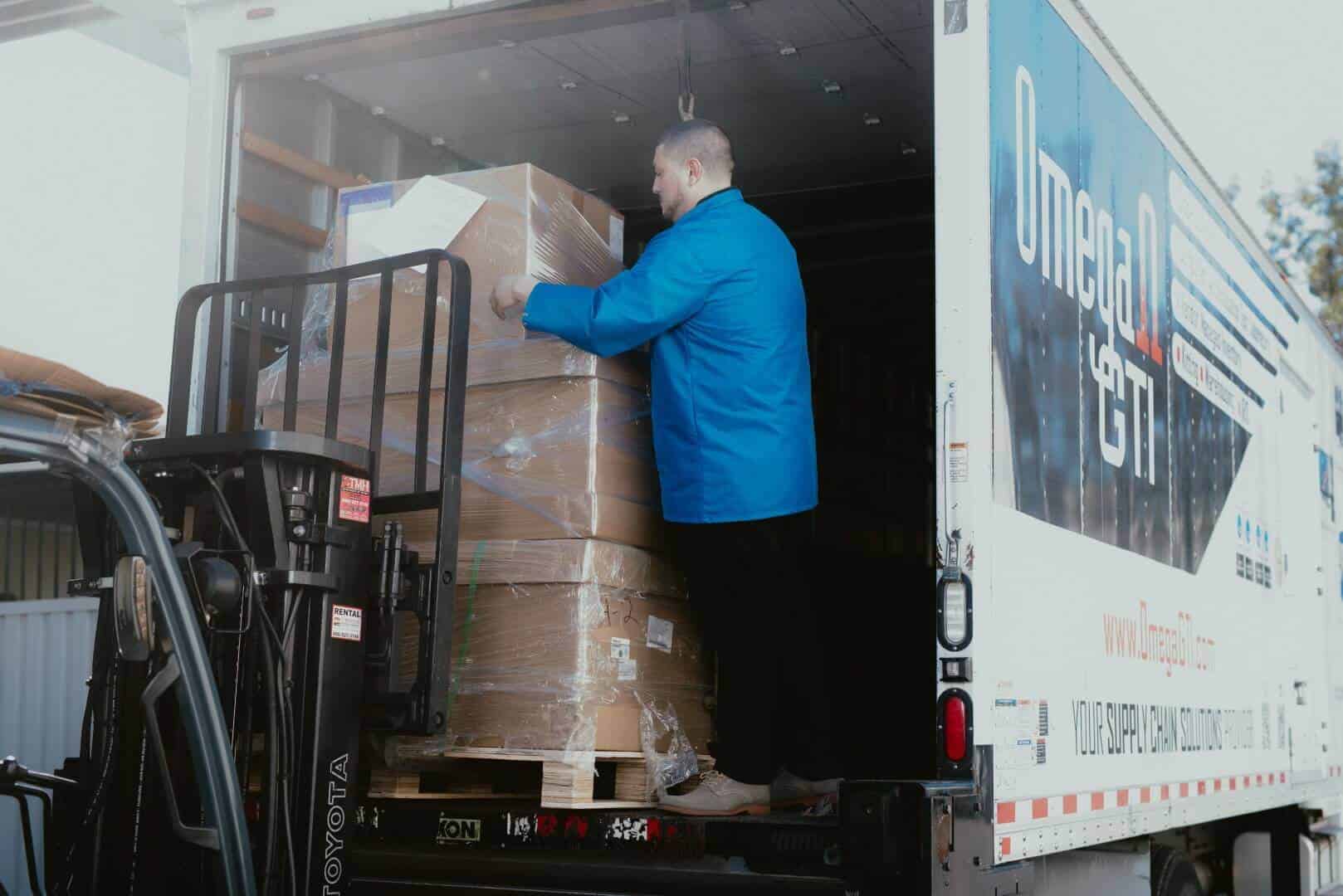 Omega GTI team member loading a shrink-wrapped inventory pallet onto an Omega GTI delivery truck